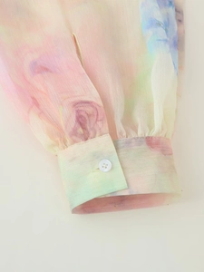 Detail of soft watercolor print sleeve with pleated cuffs and simple white button