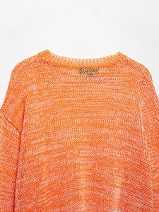 Detail of crew neck and space dye knit texture on an orange mesh crochet sweater