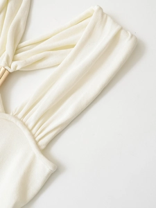 Detail of white knit dress featuring ribbed texture and elegant gold ring hardware