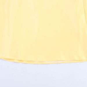 Detail of elegant yellow satin dress hem showing smooth fabric texture and neat stitching