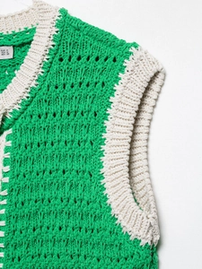 Dettaglio ravvicinato del gilet in maglia verde con bordo bianco e trama traspirante