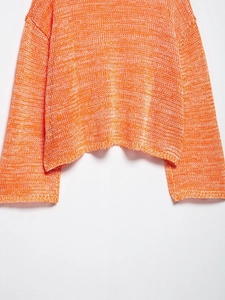 Close-up of orange and white mixed-color hollow knit texture on a loose summer sweater