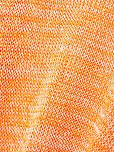 Close-up of the orange and cream hollow-out knit fabric showing textured mesh details