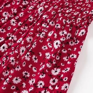 Dettaglio ravvicinato del tessuto floreale rosso con margherite e trama elastica a punto smock