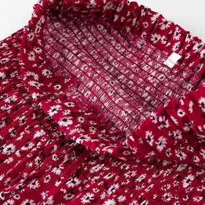 Dettaglio dell'abito rosso a fiori con elastico smock e motivi a margherite bianche