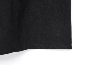 Detail shot of the black linen fabric texture and high-quality hem stitching on the dress