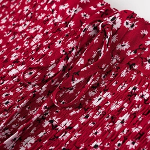 Dettaglio dell'abito rosso a fiori con vita elasticizzata a punto smock e coulisse