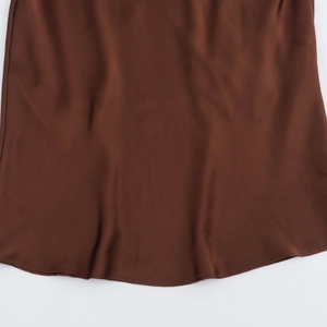 Detailed view of chocolate brown satin dress hem with smooth texture and silky sheen