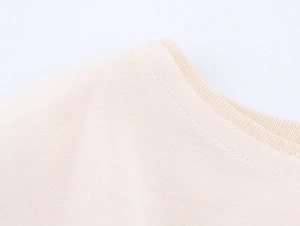 Close-up of beige knit top showing high-density fabric texture and smooth stitching detail