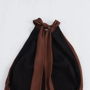 Detail of elegant black halter dress featuring a large brown satin bow tie at the neckline