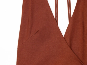Macro shot of V-neck stitching and linen texture on a burnt orange summer dress