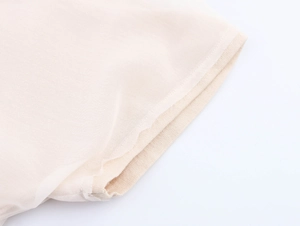 Detail of light beige shirt sleeve showing double-layered chiffon and knit fabric texture