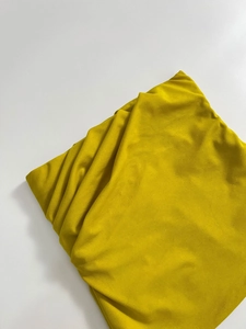 Dettaglio ravvicinato della trama in tessuto a maglia giallo senape su sfondo bianco