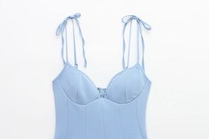 Detail of light blue bustier top featuring delicate bow straps and structured seams