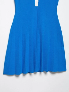 Dettaglio della texture in maglia blu della gonna a pieghe con bottone bianco