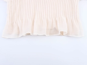 Detailed close-up of light apricot pleated sheer fabric with delicate ruffled hemline