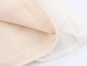 Detail view of beige knit fabric layered with white sheer chiffon material