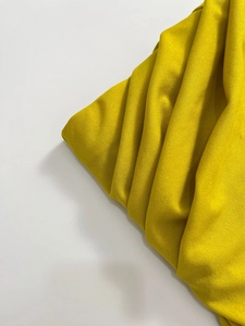 Dettaglio della texture in maglia giallo brillante con pieghe morbide e drappeggio