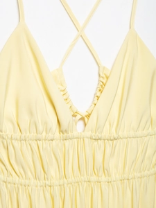 Detail of light yellow summer dress showing V-neckline with delicate ruched pleated fabric