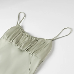 Detail of ruched sage green satin slip dress featuring elegant pleats and thin straps