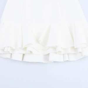 Close-up of elegant ruffled hem on a white skirt featuring refined pleated fabric details