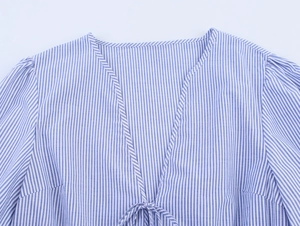 Detailed view of blue and white striped shirt with V-neckline and decorative front tie bow