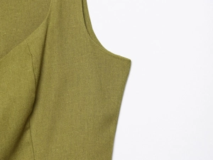 Detailed macro shot of the linen fabric texture and side stitching on the olive green dress