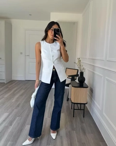Detail of a white sleeveless longline waistcoat vest with single-breasted button design