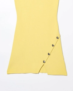 Détail de l'ourlet de robe en tricot jaune avec boutons cœur et fente latérale