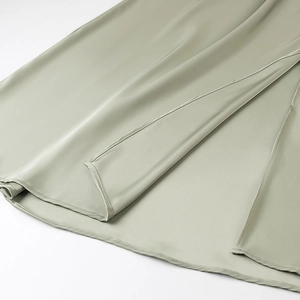 Detail of elegant sage green satin dress showing the side slit and fine stitching