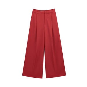 Detail view of high waisted red wide leg trousers with pleated front and smooth suit fabric