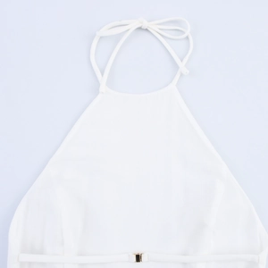 Detail of white halter neck top with thin straps and gold buckle belt accent