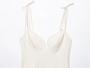 Close-up of white structured corset top with bow-knot shoulder straps and seam details
