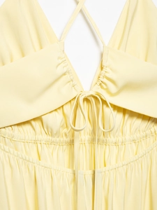 Detail of yellow backless dress with V-neck bow tie and elastic pleated waist texture