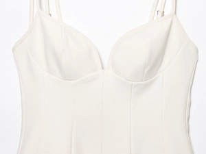 Detail of structured bustier cups and slim straps on a cream mini camisole dress