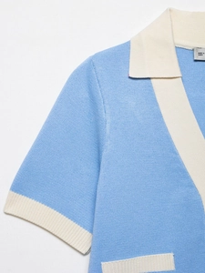 Detalle del polo de punto azul claro con ribete en contraste y textura fina