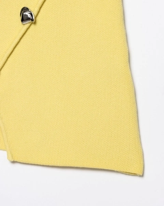 Détail de la texture en maille jaune avec un bouton métallique argenté élégant