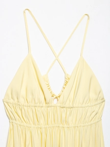 Detail of light yellow backless dress with cross straps and elastic pleated waistline