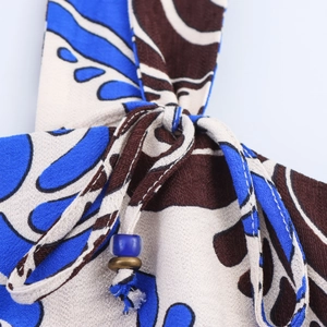 Detail of bohemian abstract print dress featuring adjustable straps with blue beads