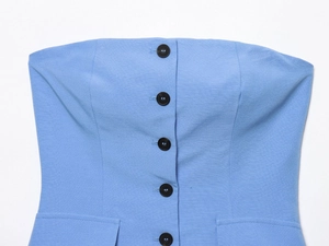 Detail of light blue strapless top featuring central black buttons and decorative pocket flaps