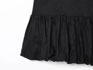 Detail of ruffled hem on a black cotton linen mini dress with a textured voluminous flare