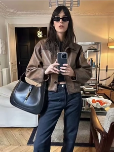 Detail of vintage brown leather jacket with black leather shoulder bag and metal buckle