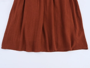Detail shot of the rust red cotton fabric texture and fine pleated hem on this dress