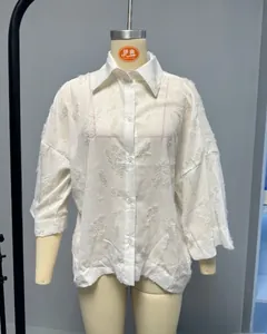 Détail de la texture jacquard blanche et du motif floral sur la chemise boutonnée femme