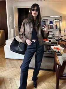 Detailed close-up of a vintage brown leather jacket and black shoulder bag on a model