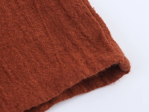 Detailed macro view of rust red woven cotton linen fabric showing natural texture and seams