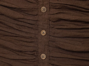 Detail of brown ruched fabric featuring a vertical button placket with three round buttons