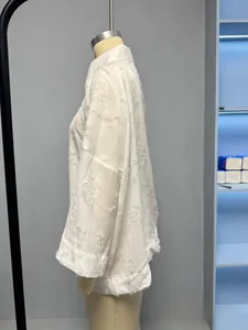 Détail de la chemise blanche à manches longues avec fleurs 3D et textures à franges