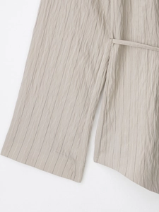 Detail view of khaki striped fabric texture with waist tie and wide cuff design