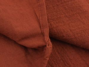Macro detail of the rust red cotton-linen fabric with professional hem stitching work
